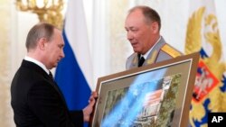 Президент России Владимир Путин получает фотографию, сделанную в Сирии, от генерал-полковника Александра Дворникова во время церемонии награждения в Московском Кремле. 17 марта 2016 г.